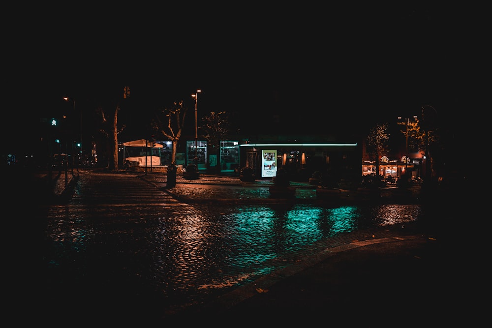 a wet street at night with a small building in the background