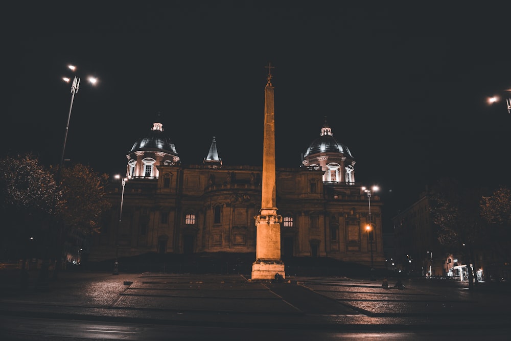 a tall monument in front of a building at night