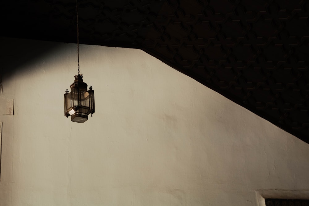 a light hanging from a ceiling next to a white wall