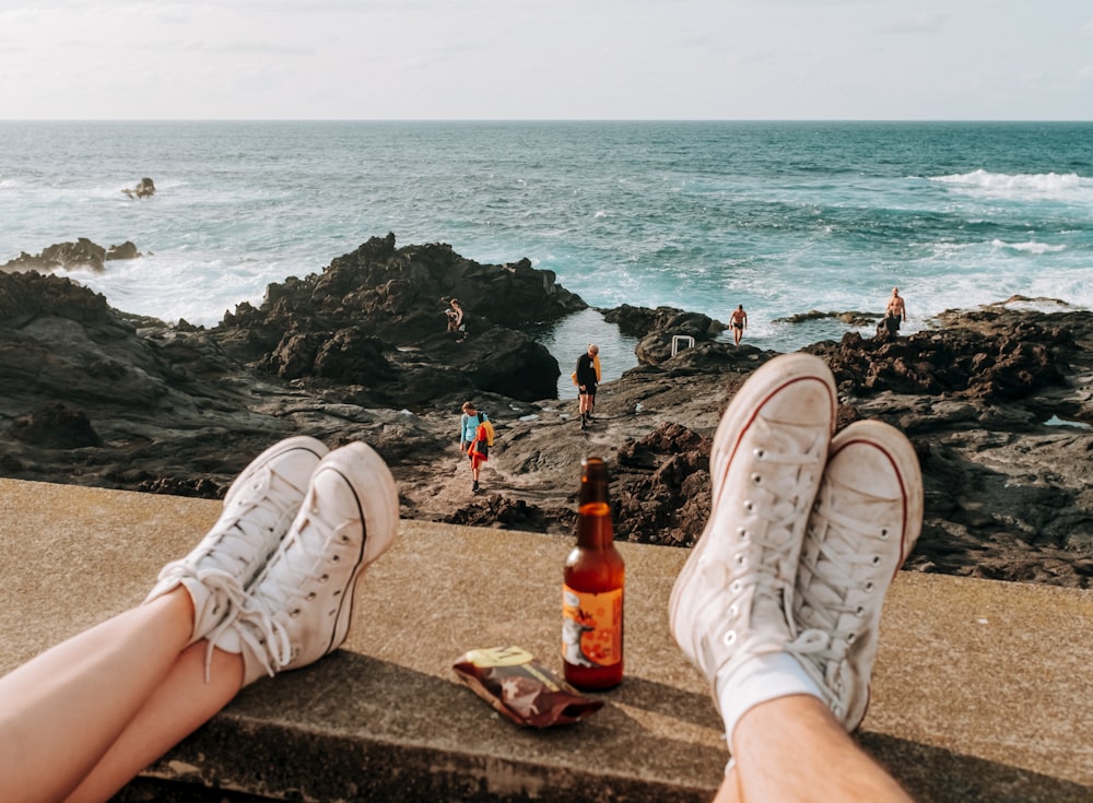 a person sitting on a ledge next to the ocean