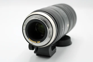 Close-up of a high-end camera lens catching light, set against a neutral backdrop.