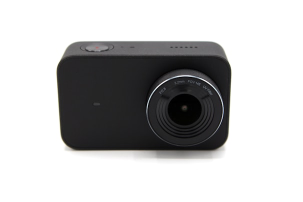 A compact, black rectangular camera with a prominent lens. The lens has markings for F2.8, 3.2mm, FOV 145, and UV filter. A small red button can be seen on the top, indicating a recording function.