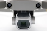 A close-up view of a drone camera, featuring lenses and sensors. The design is sleek and modern with a metallic finish.