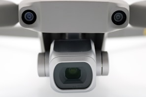 A close-up view of a drone camera, featuring lenses and sensors. The design is sleek and modern with a metallic finish.