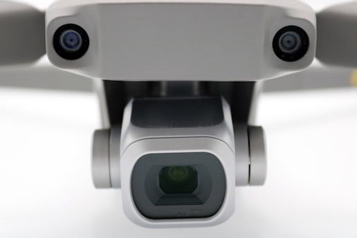 A close-up view of a drone camera, featuring lenses and sensors. The design is sleek and modern with a metallic finish.
