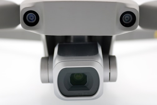 A close-up view of a drone camera, featuring lenses and sensors. The design is sleek and modern with a metallic finish.