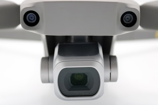 A close-up view of a drone camera, featuring lenses and sensors. The design is sleek and modern with a metallic finish.