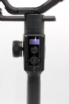 Modern video gimbal resting on a clean white surface with subtle gold highlights.