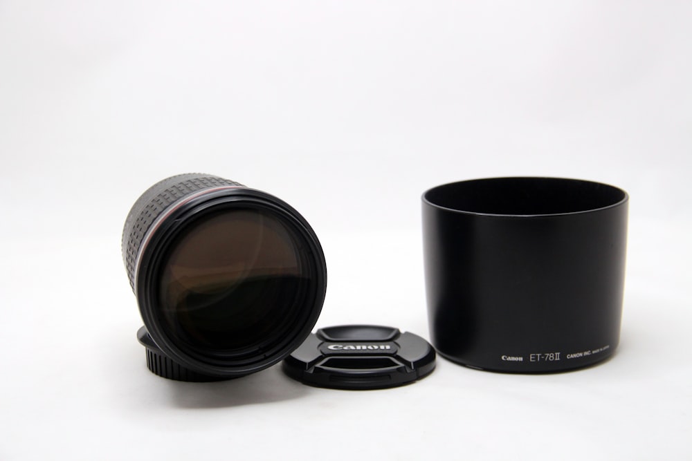 a camera lens sitting next to a black cup