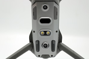 A close-up view of a drone's underside, showcasing various sensors, cameras, and LEDs arranged symmetrically along its body. The gray, metallic finish gives a sleek, modern appearance.