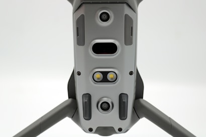 A close-up view of a drone's underside, showcasing various sensors, cameras, and LEDs arranged symmetrically along its body. The gray, metallic finish gives a sleek, modern appearance.