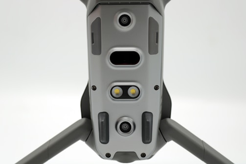 A close-up view of a drone's underside, showcasing various sensors, cameras, and LEDs arranged symmetrically along its body. The gray, metallic finish gives a sleek, modern appearance.