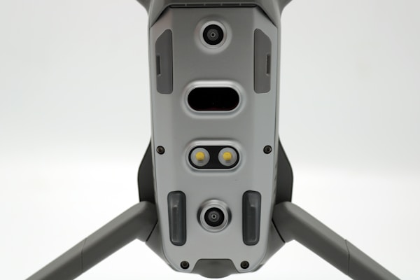 A close-up view of a drone's underside, showcasing various sensors, cameras, and LEDs arranged symmetrically along its body. The gray, metallic finish gives a sleek, modern appearance.