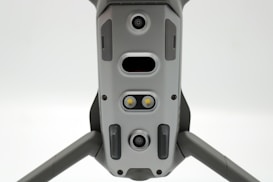 A close-up view of a drone's underside, showcasing various sensors, cameras, and LEDs arranged symmetrically along its body. The gray, metallic finish gives a sleek, modern appearance.