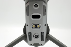 A close-up view of a drone's underside, showcasing various sensors, cameras, and LEDs arranged symmetrically along its body. The gray, metallic finish gives a sleek, modern appearance.