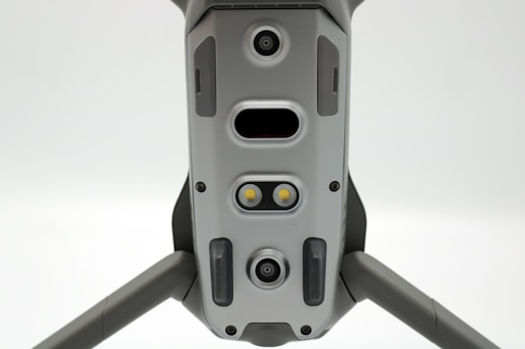 A close-up view of a drone's underside, showcasing various sensors, cameras, and LEDs arranged symmetrically along its body. The gray, metallic finish gives a sleek, modern appearance.