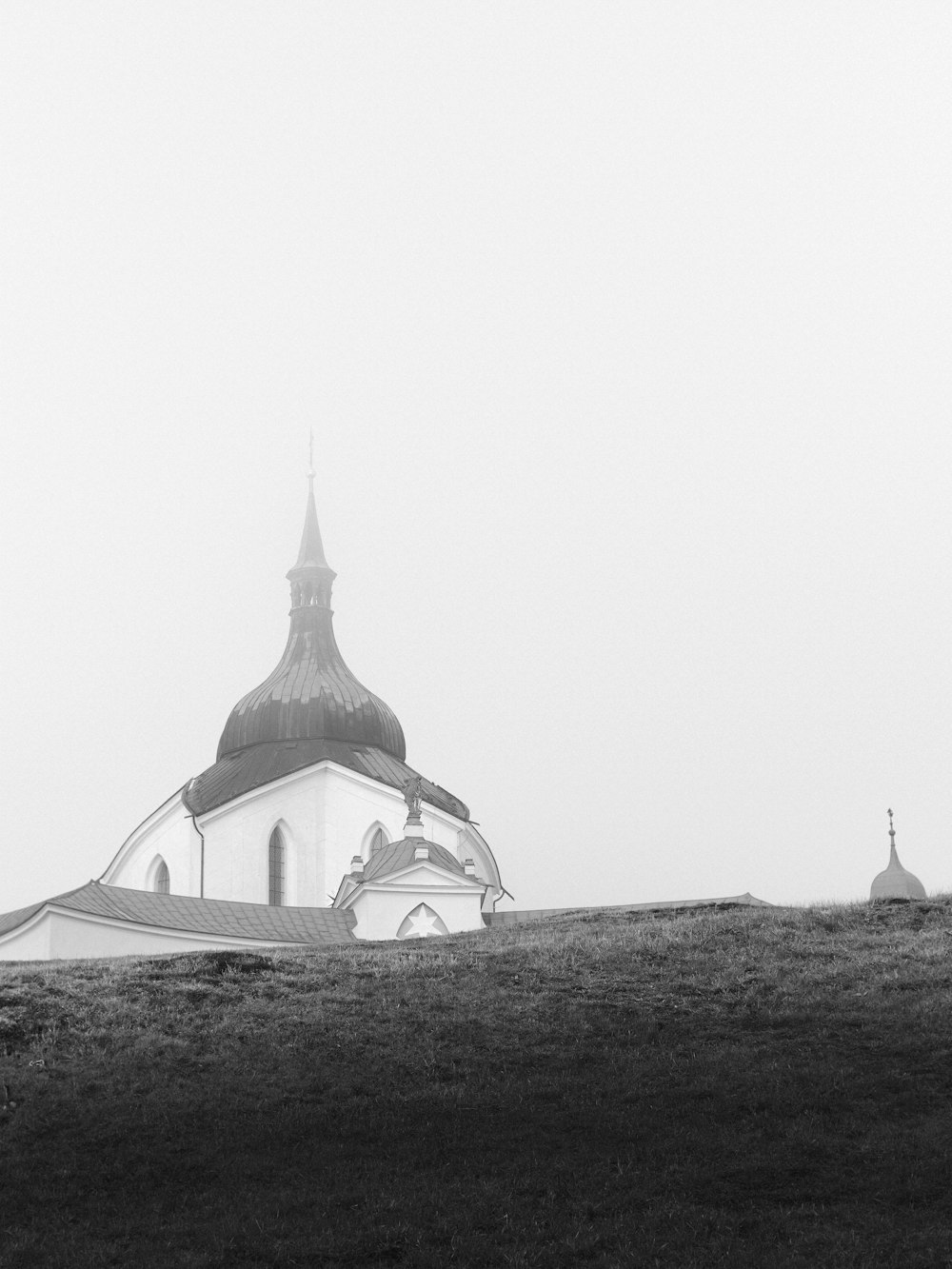 a black and white photo of a church on a hill