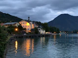 Evening view of the lakeside house with warm lights and a barbecue area.