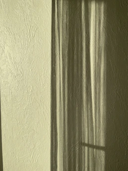 A subtle abstract shadow play on a textured wall, evoking quiet contemplation.