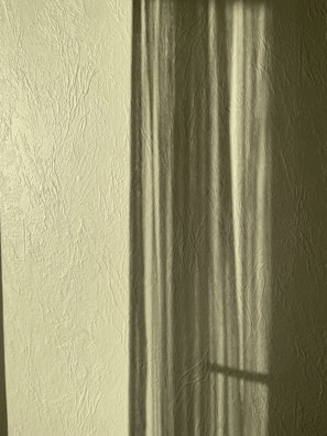 Abstract shadows and light patterns on a textured wall.