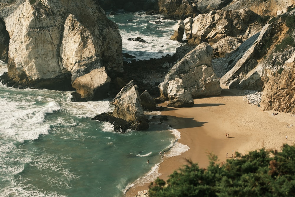 a sandy beach next to a rocky cliff