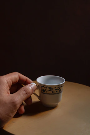 Hand holding a black ritual cup decorated with delicate patterns, glowing softly.
