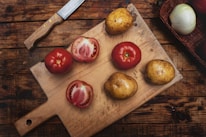 Close-up of a handcrafted wooden tool resting next to fresh farm vegetables on a rustic table.