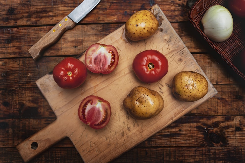 a cutting board topped with tomatoes and potatoes