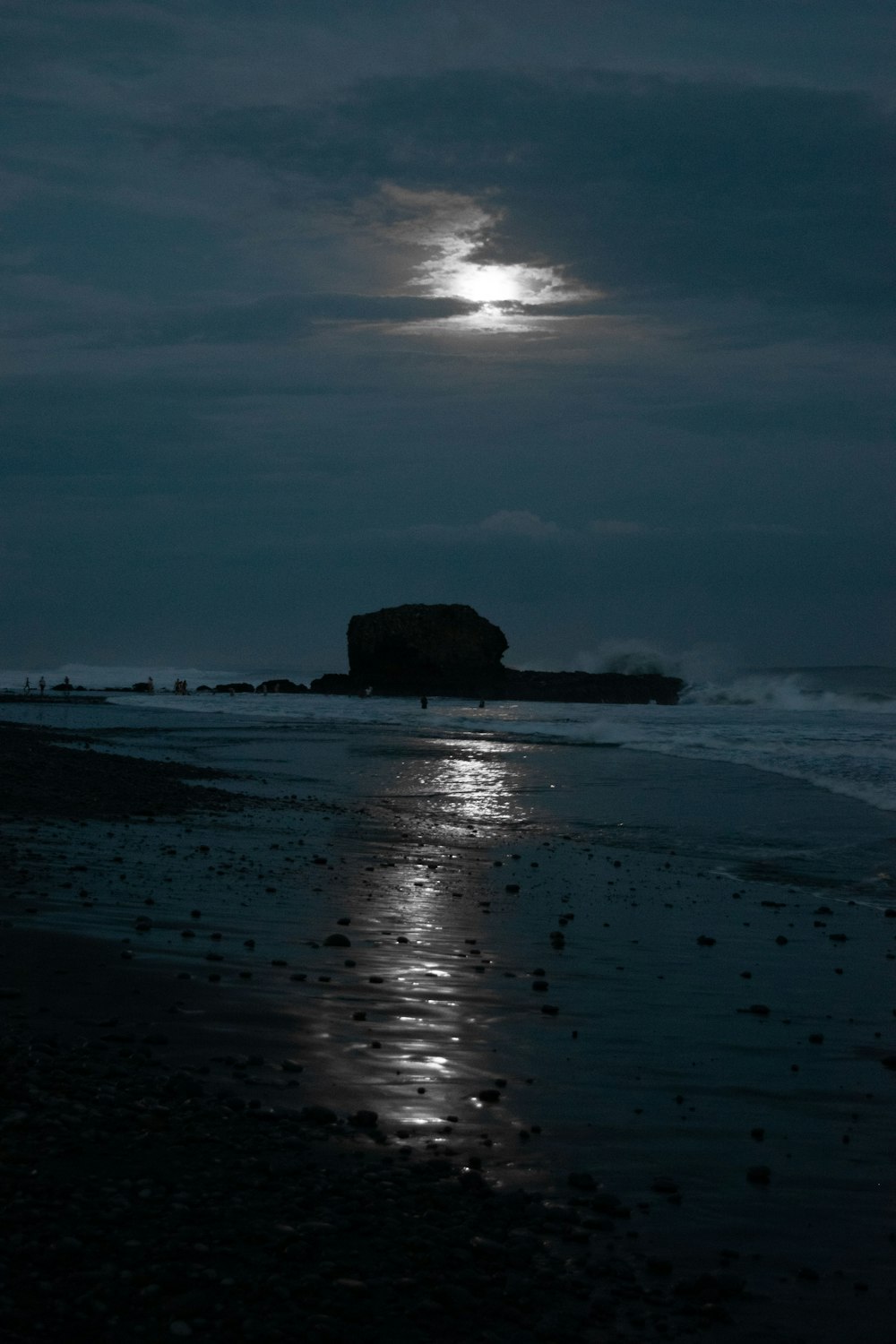 a full moon shines in the sky over a beach