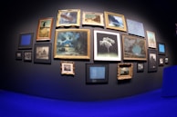 Modern gallery wall with various colorful art pieces hung evenly.
