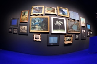 Modern gallery wall with various colorful art pieces hung evenly.