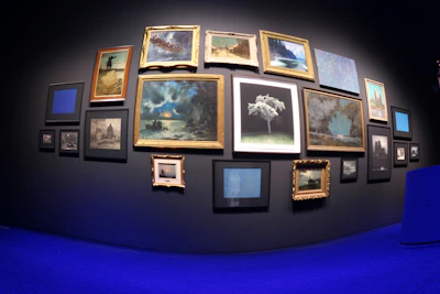 Close-up of hands arranging art pieces on a gallery wall painted in calming blue and white tones.