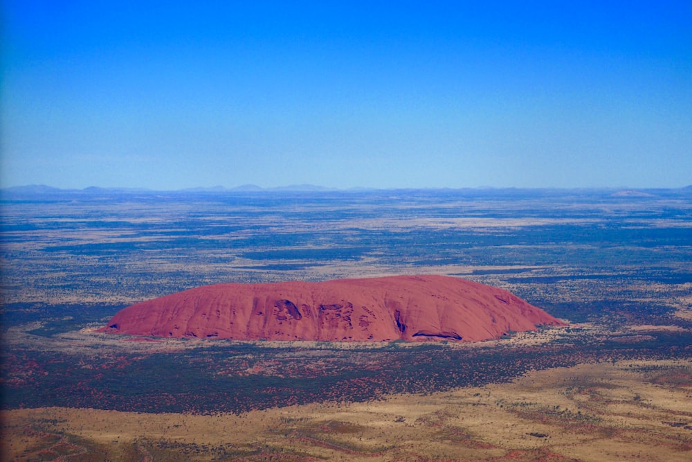 a large red rock in the middle of a desert