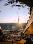 a tent with the sun setting in the background