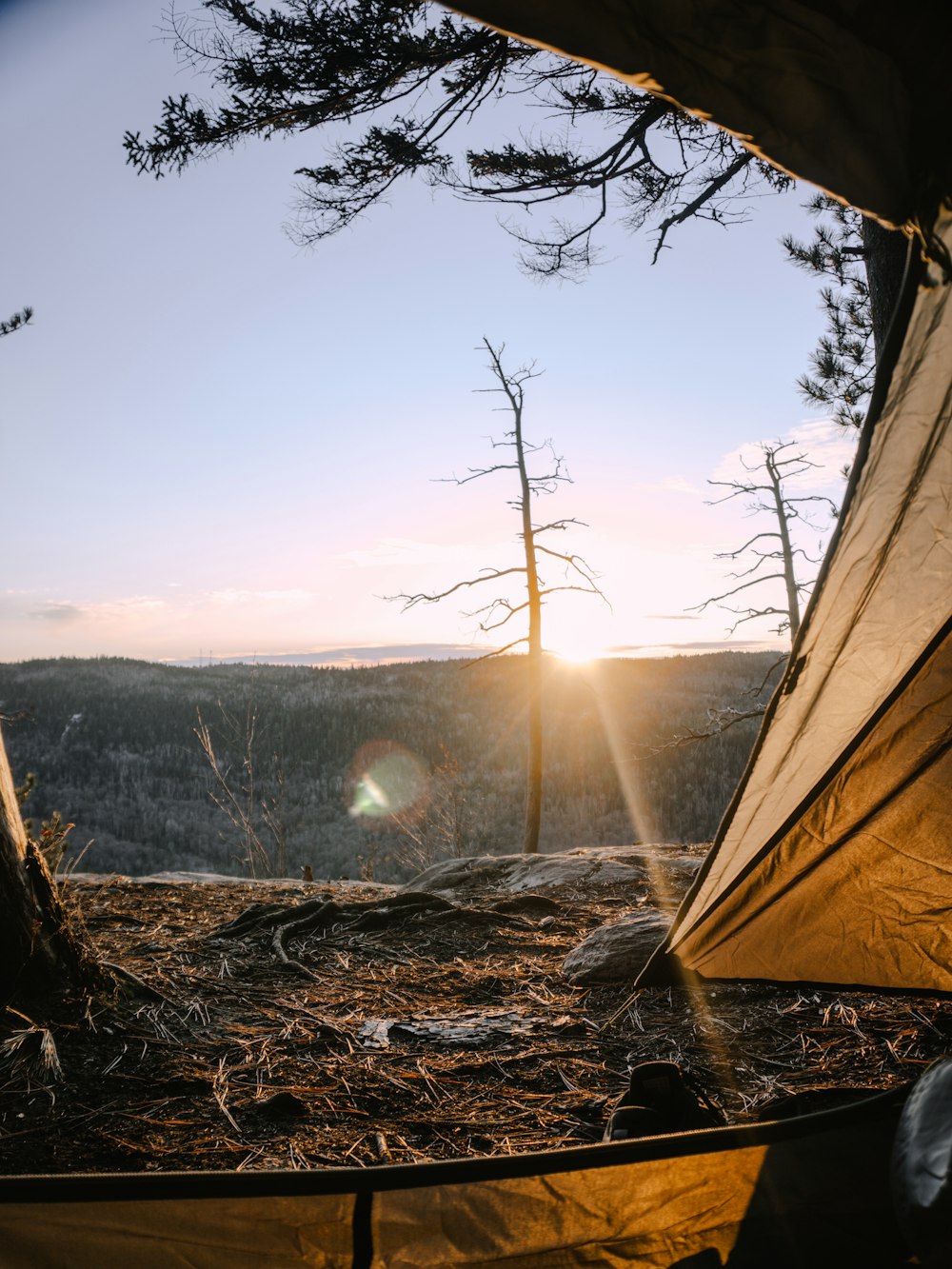a tent with the sun setting in the background