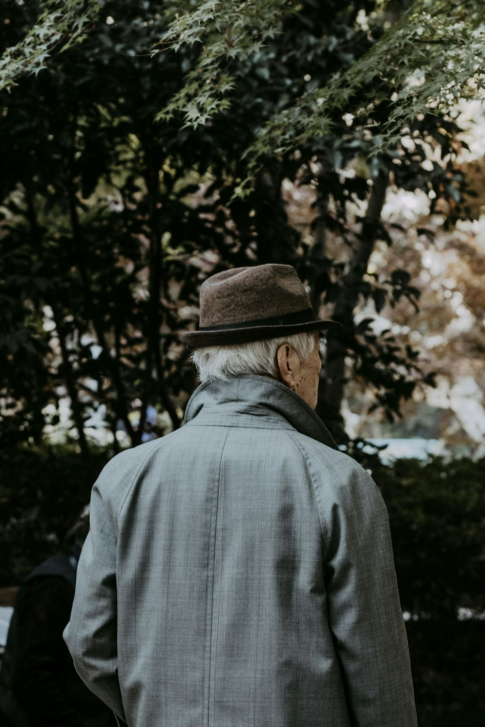 an old man with a hat is walking in the park