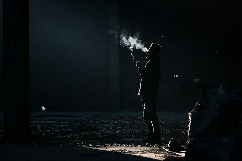 a person standing in the dark holding a cigarette