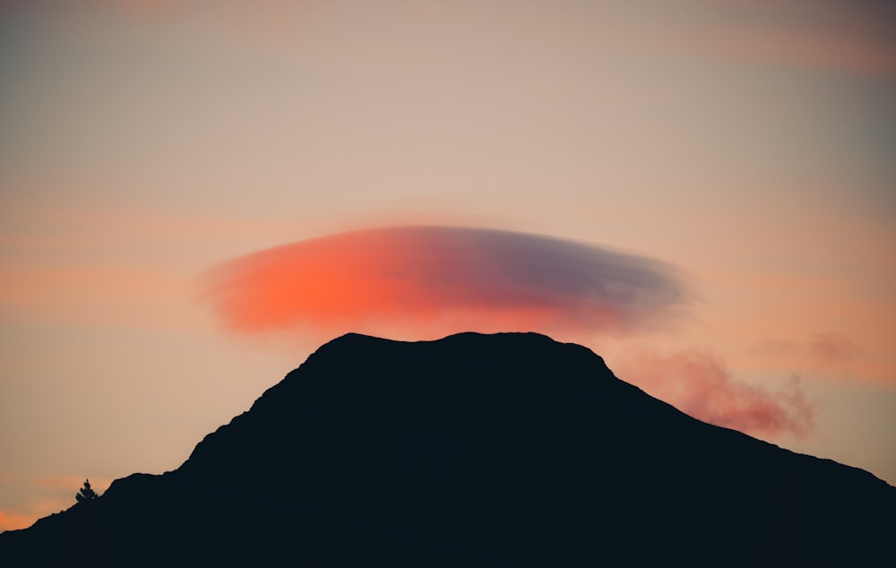 a large cloud is in the sky above a mountain