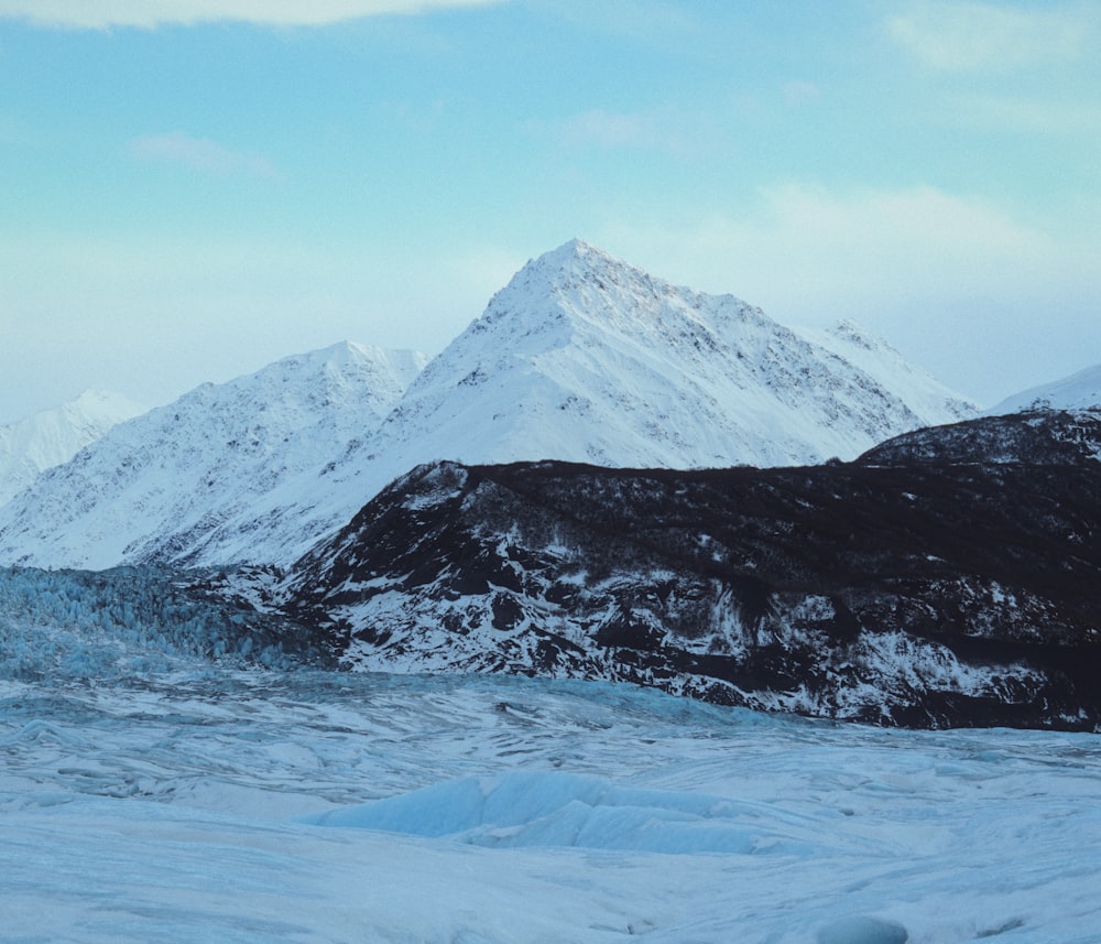 uma montanha coberta de neve com um lago em primeiro plano