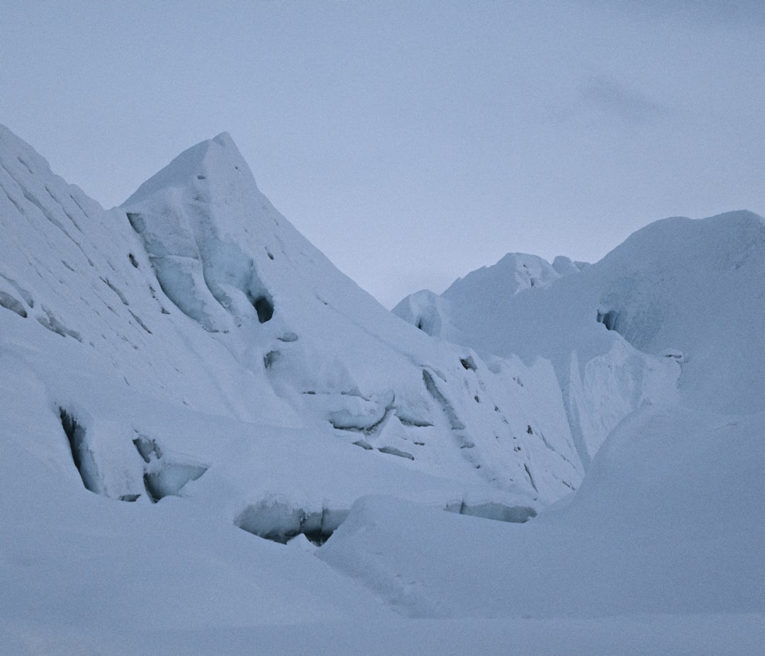 a snowboarder is going down a snowy mountain, glaicer