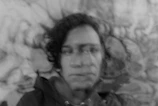 An artistic black and white portrait with fragmented facial features blending into the background.