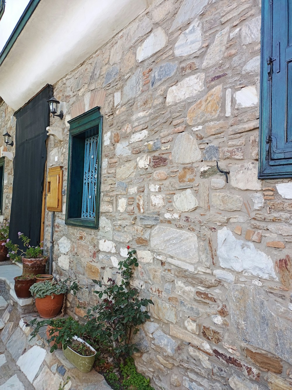 un bâtiment en pierre avec des volets et des fenêtres bleus