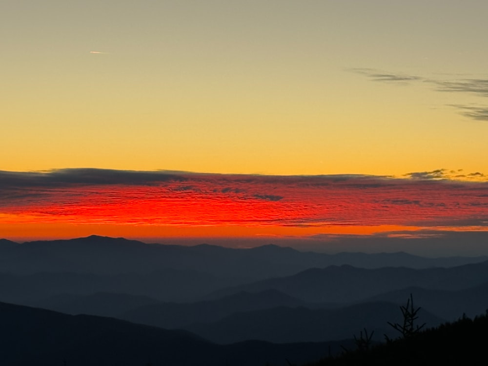 the sun is setting over a mountain range