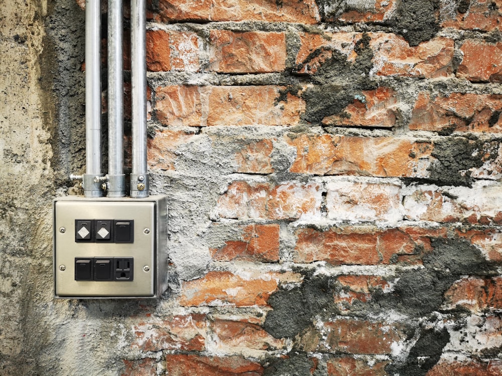 a brick wall with two metal pipes attached to it