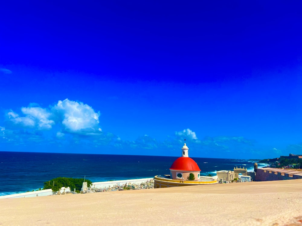 Un edificio rojo y blanco sentado en la parte superior de una playa de arena