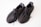 A pair of dark-colored knitted sneakers with thick rubber soles and detailed stitching. The shoes have black laces and a breathable fabric design. The insoles display logos.