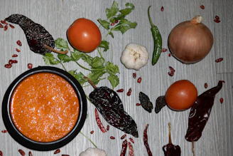 Close-up of vibrant gourmet chili sauces in rustic bowls with fresh ingredients around.