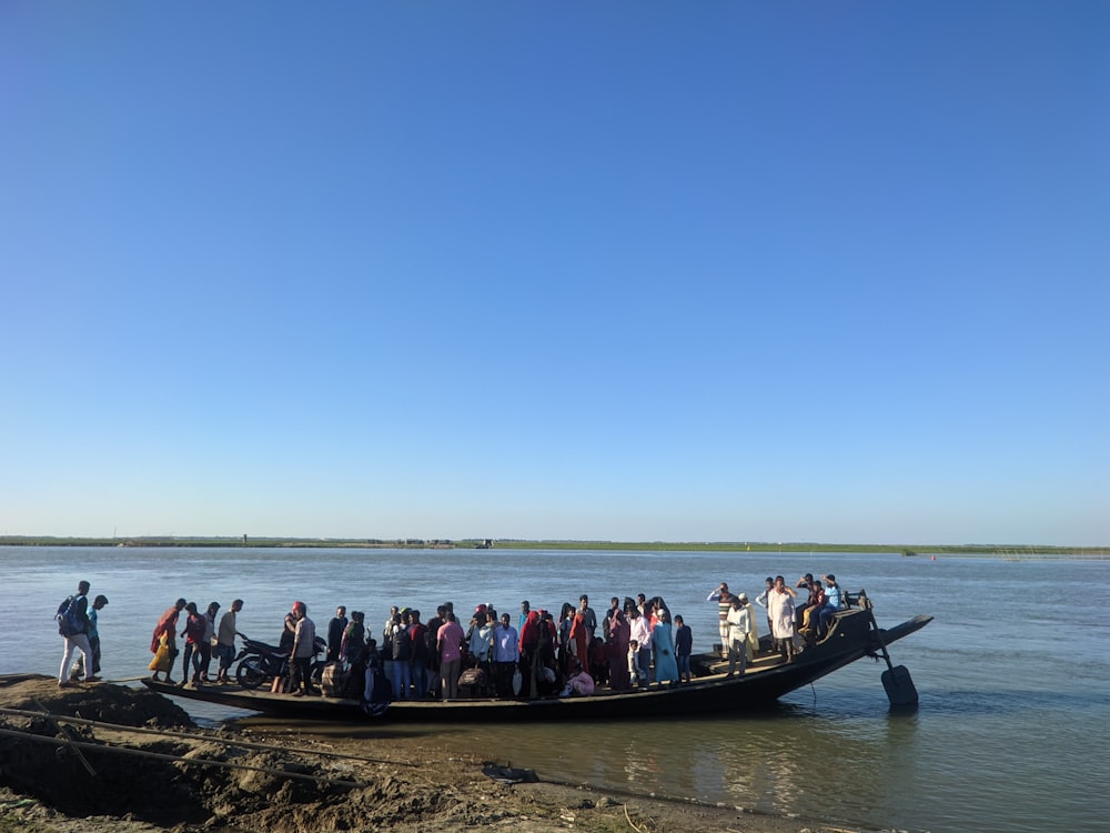 a large group of people standing on the back of a boat