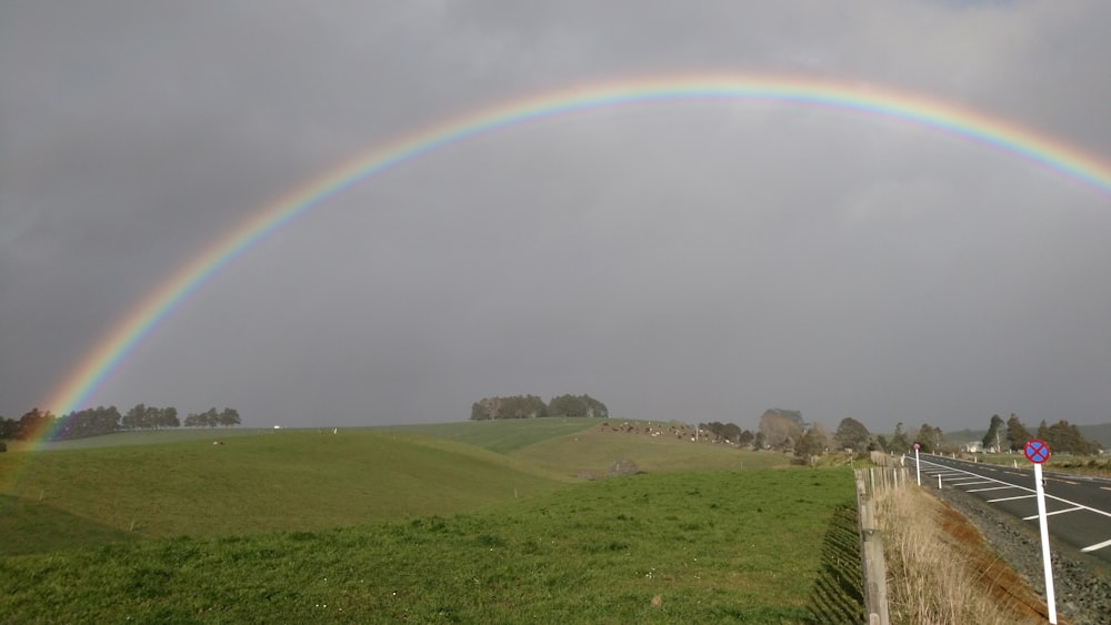 um arco-íris duplo é visto sobre uma estrada