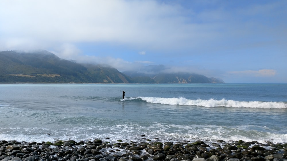 una persona montando una ola encima de una tabla de surf